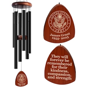May include: A wooden wind chime with a black metal chime tube and a wooden plaque with the text "UNITED STATES ARMY James Grant 1955-2025" and a second plaque with the text "They will forever be remembered for their kindness, compassion, and strength".