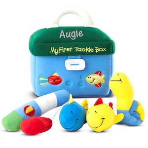 May include: A blue plush tackle box with a green lid and white handle, embroidered with "Augie" and "My First Tackle Box." Includes plush fish, a worm, and a fishing rod. The tackle box is approximately 8 inches wide.