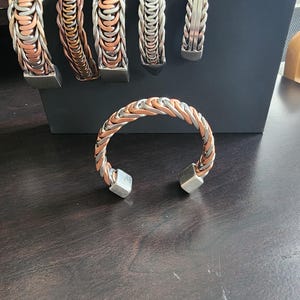 May include: Five silver and copper bracelets with a braided design. One bracelet is a cuff with square ends.
