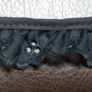May include: Black lace trim with a scalloped edge and a delicate floral pattern.