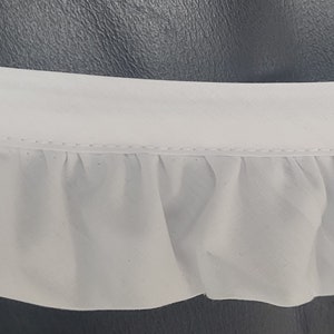 May include: White ruffled trim with a stitched edge. The trim is made of a soft, lightweight fabric.