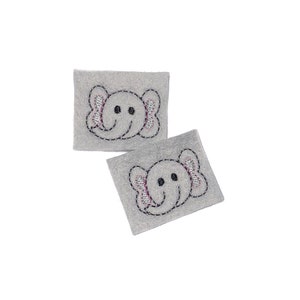 May include: Two gray felt patches with embroidered elephant faces. The elephants have black eyes, pink ears, and a black outline.
