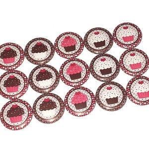 May include: A set of 12 round cupcake-themed buttons with pink and brown frosting and sprinkles. The buttons have a white background with a brown and pink polka dot pattern.