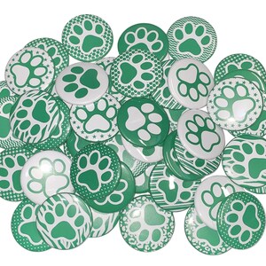 May include: A collection of green and white paw print buttons. The buttons have different patterns, including polka dots, stripes, and zigzags.