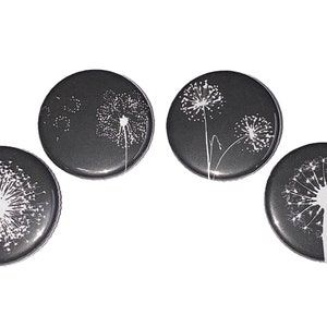 May include: Four round black buttons with white dandelion designs. Each button features a different dandelion design.