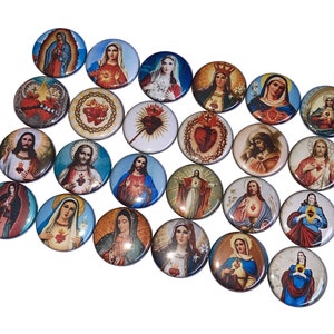 May include: A collection of 20 round button pins featuring religious imagery. The pins depict various saints and religious figures, including the Sacred Heart of Jesus and the Virgin Mary. The pins are colorful and feature intricate details.