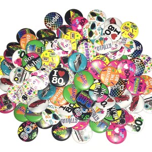 May include: A collection of colorful 80s themed buttons with various designs and slogans, including "I Love 80s", "Totally Rad", "Survived the 80s", "Gnarly", and "80s Baby".