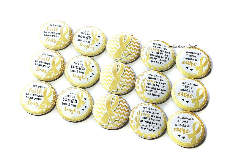 May include: A set of 10 yellow and white round buttons with gold ribbon designs and inspirational messages. The messages include "Let your faith be stronger than your fear", "Life is tough but I am tougher", and "We don't know how strong we are until being strong is the only choice we have".  The buttons also feature the message "Someone I love needs a cure".