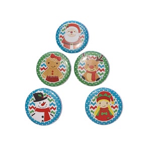 May include: Five Christmas themed button pins. The pins feature a gingerbread person, Santa Claus, a reindeer, a snowman, and an elf. The pins are all on a white background.