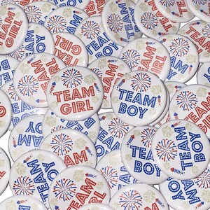 May include: A collection of round, white buttons with red, white, and blue firework designs. The buttons have the text "Team Girl" and "Team Boy" printed on them.