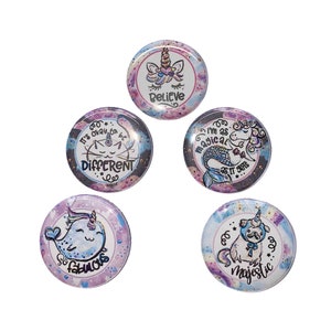 May include: Five round, colorful buttons with a white background and a sparkly, glittery effect. Each button features a different cartoon animal with a motivational quote. The quotes are: "Believe", "It's okay to be different", "I'm as magical as it gets", "So fabulous", and "Majestic".