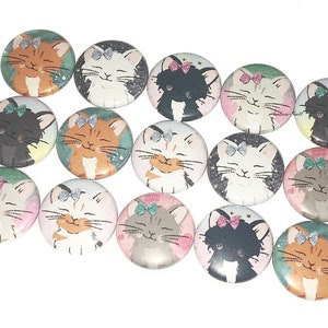 May include: A set of 14 round buttons featuring various cute cats with bows. The cats are depicted in different colors and poses, including orange, white, black, and gray. Each button has a white background with a subtle glitter effect.