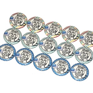 May include: A set of 15 round, blue, green, yellow, and red buttons with the text "Keep Calm and Code On" printed on each button.