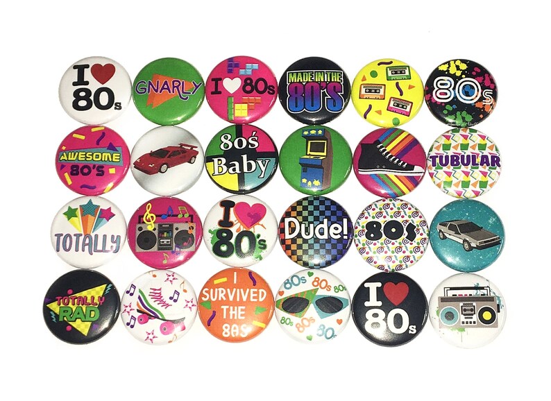 May include: A collection of 18 round buttons with various 1980s themed designs. The buttons feature bright colors, bold graphics, and text such as "I Love 80s", "Gnarly", "80s Baby", "Totally Rad", "Dude!" and "I Survived the 80s".