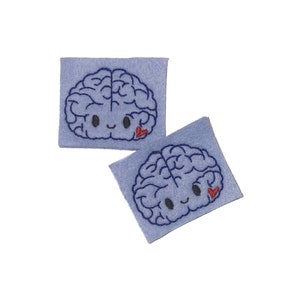 May include: Two blue felt patches with embroidered cartoon brains. Each brain has a small red heart on the right side.