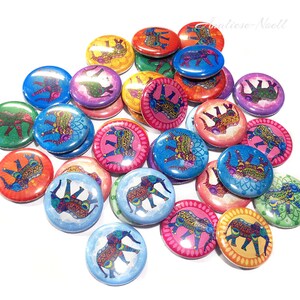 Op de afbeelding: Een verzameling ronde, kleurrijke knopen met een ingewikkeld olifantendesign. Elke knop heeft een andere achtergrondkleur en een gedetailleerde olifantenillustratie met een mandala-achtig patroon.