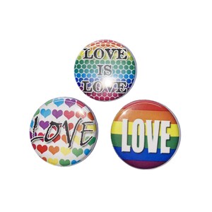 May include: Three round button pins with rainbow designs. The first pin has a rainbow background with a honeycomb pattern and the text "LOVE IS LOVE". The second pin has a white background with rainbow hearts and the text "LOVE". The third pin has a rainbow stripe background with the text "LOVE" in white.