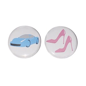 May include: Two button pins, one with a blue car and the other with two pink high heels.