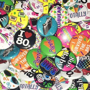 May include: A collection of colorful 80s themed buttons with various designs and slogans, including "80's Baby", "I Love 80's", "Totally Tubular", "Gnarly", "I Survived the 80s", and "Made in the 80's".