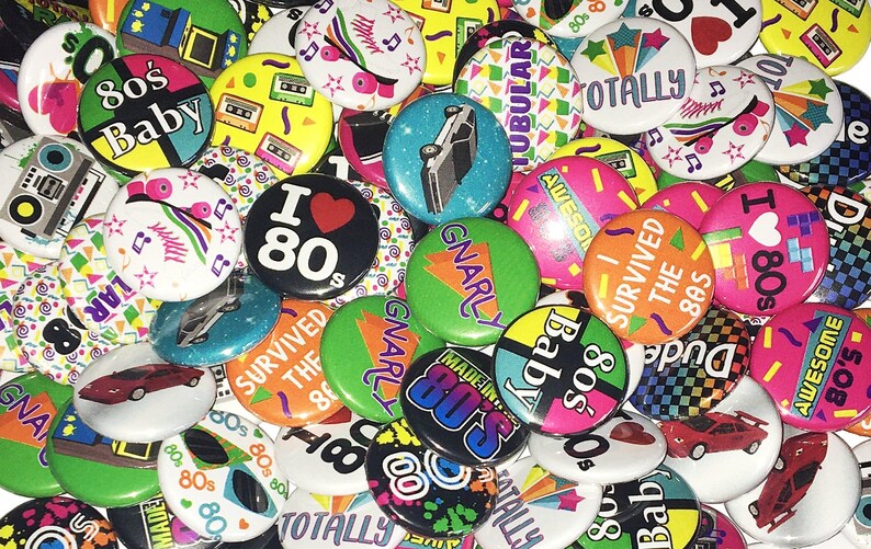 May include: A collection of colorful 80s themed buttons with various designs and slogans, including "80's Baby", "I Love 80's", "Totally Tubular", "Gnarly", "I Survived the 80s", and "Made in the 80's".