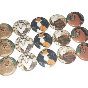 May include: A set of 12 round buttons featuring various animal illustrations. The buttons are brown, white, blue, orange, and green with a variety of animal designs including bears, wolves, foxes, eagles, and horses.