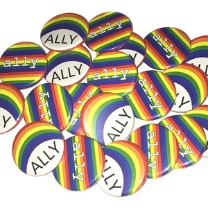 May include: A pile of rainbow-colored round buttons with the word "ALLY" printed in white on each button.