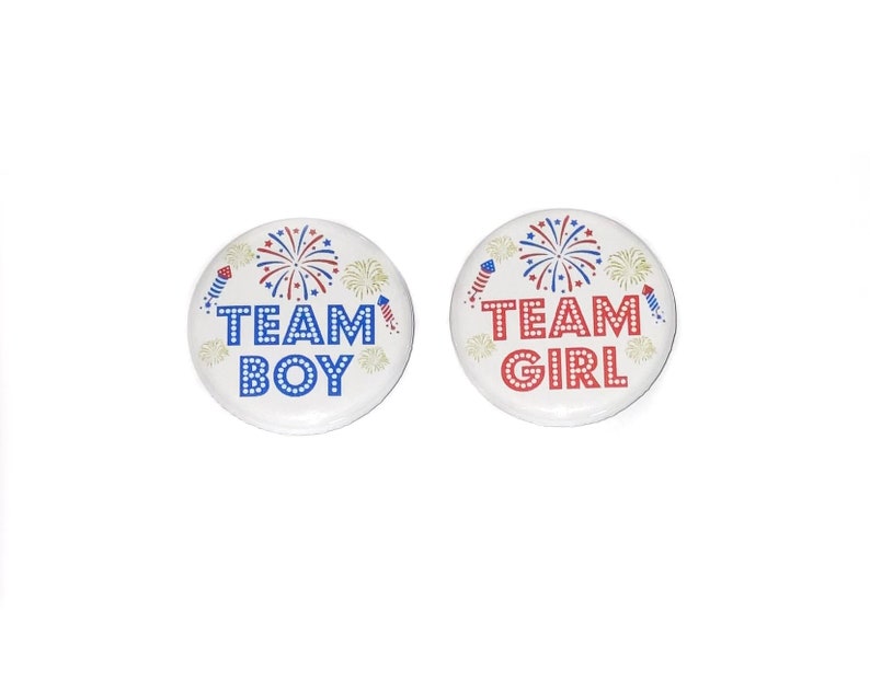 May include: Two round buttons with red, white, and blue firework designs. The left button says "Team Boy" in blue letters. The right button says "Team Girl" in red letters.
