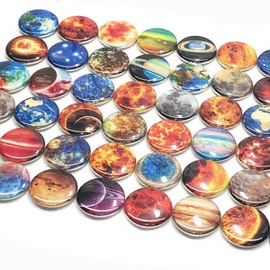 May include: A collection of 36 round, colorful buttons featuring images of planets and celestial bodies. The buttons are arranged in a semi-circle pattern, with the sun, earth, and moon prominently displayed.