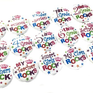 May include: A collection of 15 colorful round buttons with various school-themed messages, such as "Teachers Rock", "My Teacher Rocks", "Kindergarten Rocks", "1st Grade Rocks", "2nd Grade Rocks", "3rd Grade Rocks", "4th Grade Rocks", "5th Grade Rocks", "6th Grade Rocks", "Pre-School Rocks", "School Rocks", "My Class Rocks", "Smart Girls Rock", and "Home School Rocks". Each button features a crown and stars.