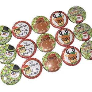 May include: A collection of Christmas-themed pinback buttons. Designs include a snowman, gingerbread man, reindeer, and Santa Claus, all wearing glasses. Text on the buttons reads "'tis the season to be nerdy", "50% naughty 50% nerdy", and "have yourself a nerdy little Christmas".