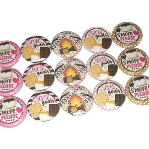 May include: A set of 12 round, 1.5 inch diameter, printed buttons featuring a campfire, s'mores, and the text "Squad Goals" and "S'more Please".