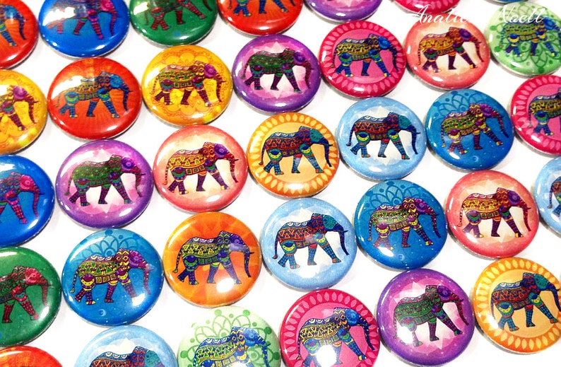 Op de afbeelding: Een verzameling kleurrijke ronde knopen met ingewikkelde gepatroneerde olifanten. Elke knop heeft een andere achtergrondkleur en een uniek ontwerp.