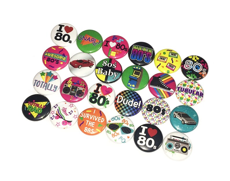 May include: A collection of 18 colorful 80s themed buttons with various designs and slogans, including "I Love 80s", "Totally Rad", "Gnarly", "Made in the 80s", "80s Baby", "Dude!" and "Tubular".