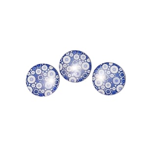 May include: Three round, blue and white patterned buttons with a white background and blue circles of varying sizes.
