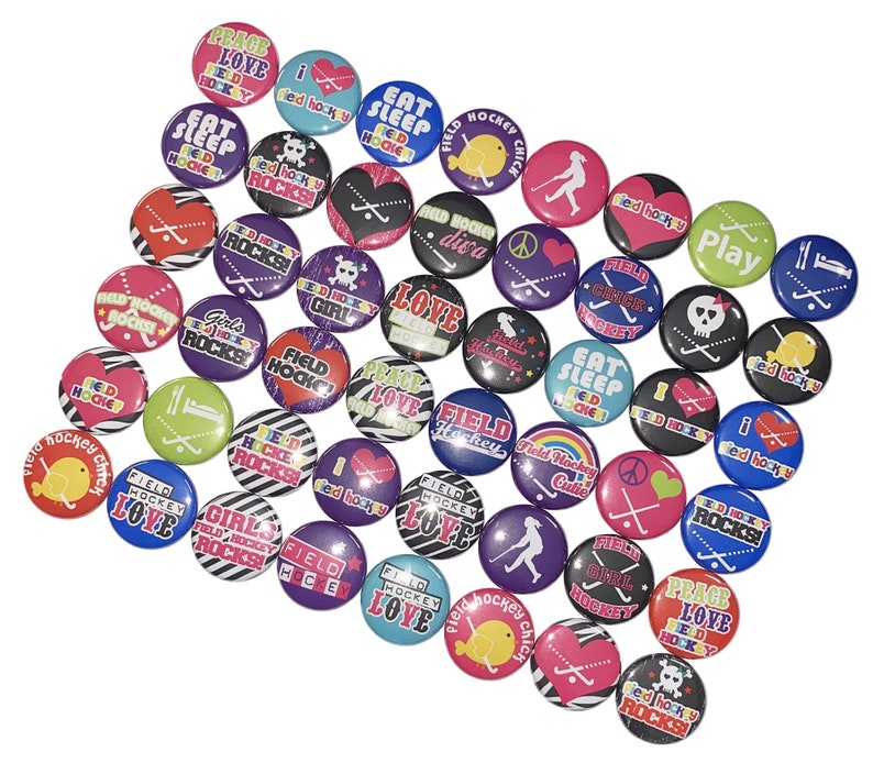 May include: A collection of colorful round buttons with various field hockey-themed designs. The buttons feature phrases like "Peace Love Hockey", "Field Hockey Cutie", "Girls Field Hockey Rocks", and "Eat Sleep Hockey".