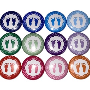 May include: A set of 16 baby footprint buttons in various colors, including blue, green, red, yellow, and purple. Each button features a white footprint design with a white polka dot border.