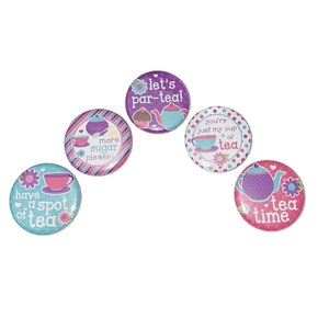 May include: Five round, colorful tea-themed buttons with various designs and text. The buttons feature teacups, teapots, and phrases like "have a spot of tea" and "let's par-tea!" against a white background.