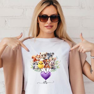 May include: White t-shirt with a graphic of a group of cartoon animals holding a purple heart balloon. The balloon has the text "bts" written on it.