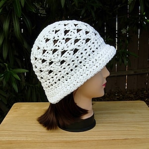 May include: White crocheted hat with a wide brim and a lacy design. The hat is made with a delicate stitch pattern and has a soft, airy feel.