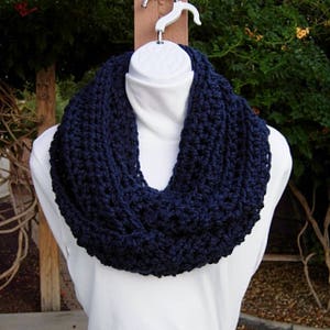 May include: A navy blue crocheted infinity scarf. The scarf is thick and textured, and it is shown on a white mannequin.