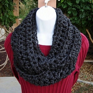 May include: A charcoal gray crocheted infinity scarf. The scarf is made with a chunky yarn and has a simple, textured stitch.