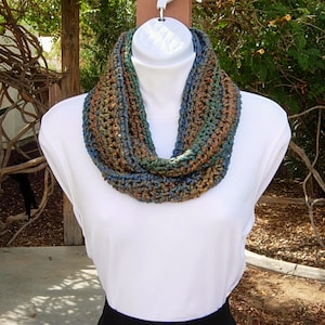 May include: A crocheted infinity scarf in shades of brown, blue, and green. The scarf is made with a chunky yarn and has a simple, textured stitch.