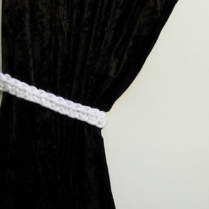 May include: Black velvet curtain with a white crocheted tieback.