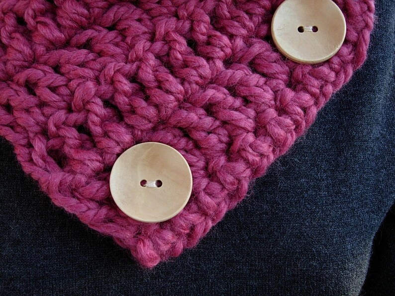 May include: A close-up of a pink knitted scarf with two wooden buttons. The buttons have a single hole in the center.