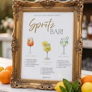 Könnte beinhalten: Ein goldgerahmtes Schild zeigt eine Spritz Bar-Menükarte. Die Karte enthält Rezepte für Aperol, Limoncello und Hugo Spritz, jeweils mit Illustrationen. Orangen und Zitronen sind vor dem Schild auf dem Tisch platziert.