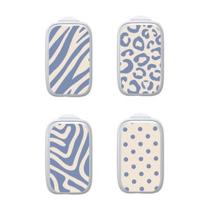 K&ouml;nnte beinhalten: Vier rechteckige Klebeabdeckungen f&uuml;r medizinische Ger&auml;te, jede mit einem eigenen Muster in Kornblumenblau und Creme. Die Designs umfassen Zebrastreifen, ein Leopardenmuster, wellenf&ouml;rmige Linien und ein klassisches Punktmuster.