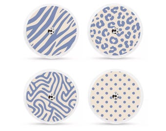 May include: Four round adhesive patches with decorative patterns. Designs include blue zebra stripes, blue leopard spots, blue squiggles, and blue polka dots. Each patch has a small, central, black and white detail.