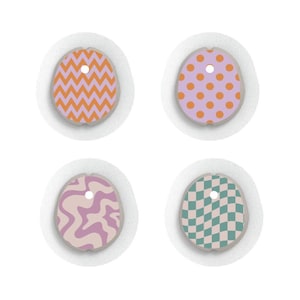 Peut inclure: Quatre ornements décoratifs en forme d'œuf avec un trou en haut pour les suspendre. Chaque œuf présente un motif différent : des zigzags orange, des pois orange, des tourbillons roses et violets et un motif à carreaux verts et bleus.