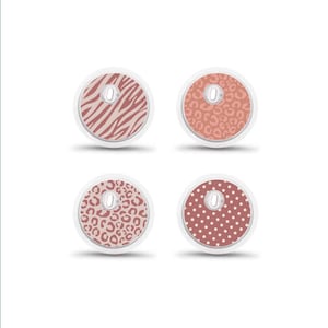 Op de afbeelding: Vier ronde covers voor volgapparatuur met verschillende patronen in oudroze en wit. De ontwerpen omvatten zebrastrepen, een luipaardprint, een patroon met jachtluipaardvlekken en een klassiek wit stippenmotief op een roze achtergrond.