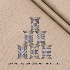 May include: Six decorative thread spools with blue and white cross-stitch patterns, including hearts and snowflakes, stacked on a beige fabric. The image includes the text: .EXP .DST .PES .PEC .HUS .JEF .VIP .VI3 .XXX. The spools are arranged on a beige fabric background.